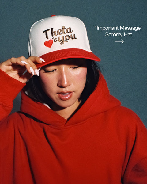 Girl wearing a red hoodie and sorority hat that says "Theta loves you". Link leads to "Important Message" sorority hat.